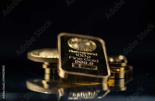 Gold bars and gold coins on a black background. Selective focus.