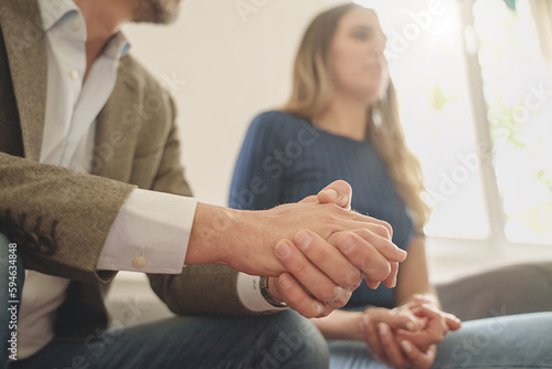 Embarrassed Couple at Family Therapist - Man's hands reveal discomfort, uneasy woman in the background, both sitting on a couch in a therapy session Fototapet