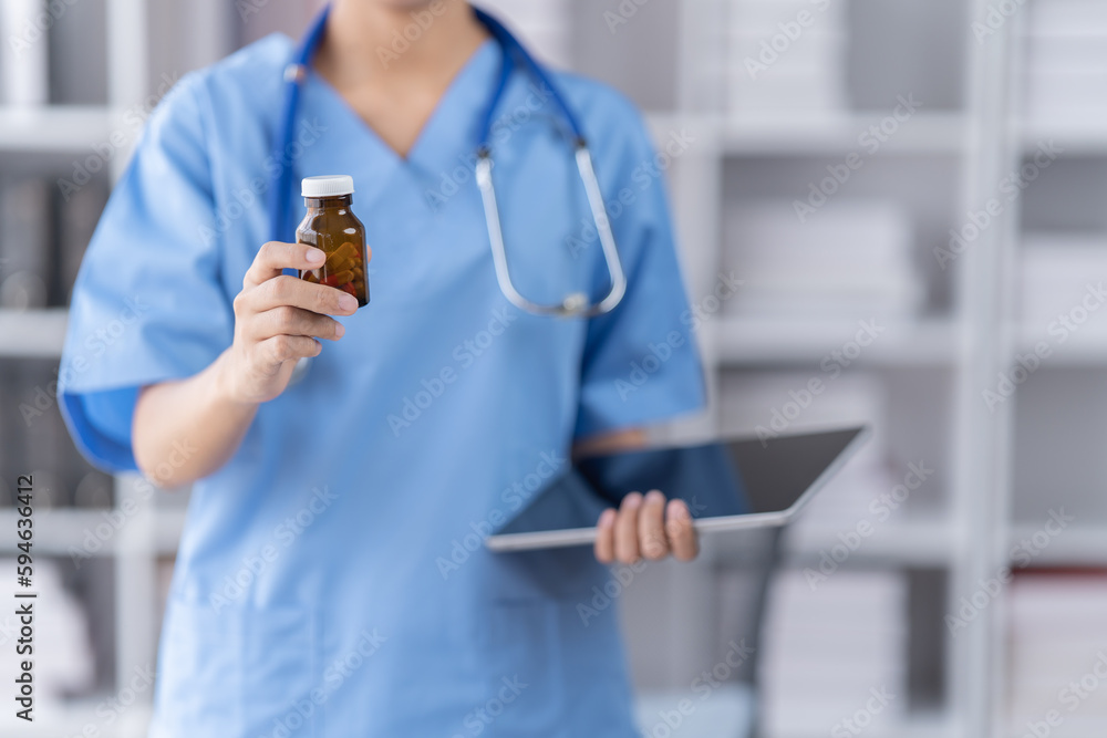Smiling of doctor recommends taking medicine, supplement, vitamins, Practitioner with bottle of pills. white plastic pill bottle on doctor wooden table. Smiling of doctor recommends taking medicine, supplement, vitamins, Practitioner with bottle of pills. white plastic pill bottle on doctor wooden table.