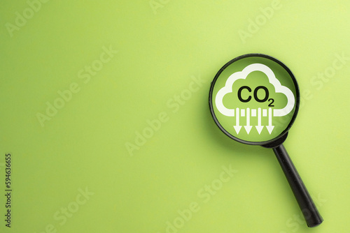 Reduce Co2,Carbon Reduction,Carbon dioxide emissions, carbon footprint concept.,Magnifying glass focus on magnifier glass with icon on green background with copyspace use for environmental idea. photo