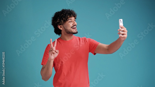 Photography handsome cheerful smiling Indian man extends hand with smartphone, taking selfie
