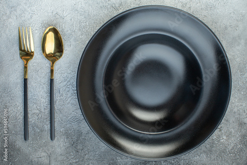 Close up shot of black dinnerware set and cutlery set on isolated gray ice background with free space