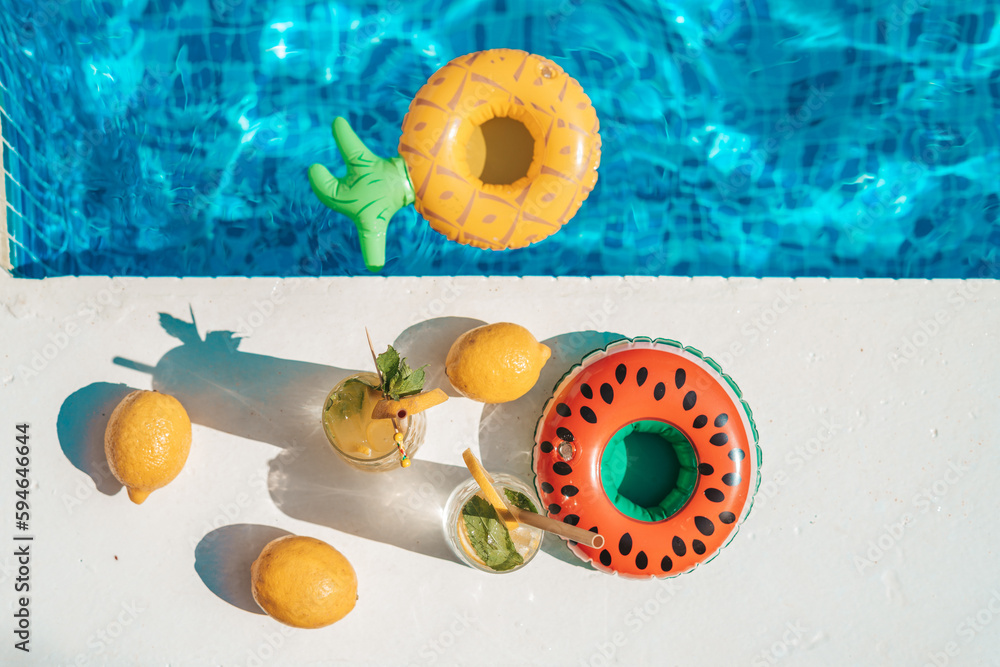 Drink at poolside. Cocktail at swimming pool with inflatable rings. Vacation, beach, summer travel concept