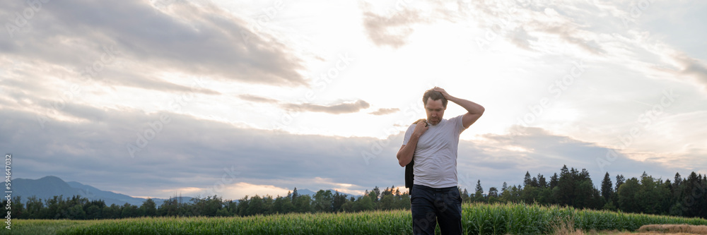 Wide view image of stressed or worried young man standing in beautiful summer nature