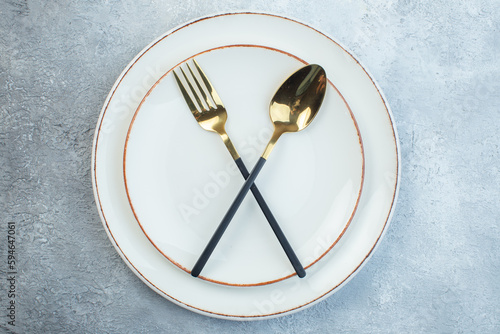 Close up view of elegant cutlery set on empty white soup plate in two sizes on half dark light gray background with distressed surface with free space photo