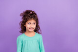 Photo of adorable tricky small kid wear turquoise shirt looking empty space isolated purple color background