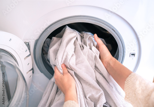 Unrecognizable woman doing laundry with washing machine at home, eco cleaning housework concept