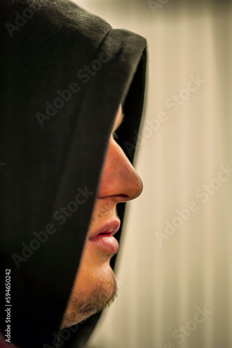 Gesichtsshilouette eines Mannes mit Bart versteckt hinter einer schwarzen Kapuzze