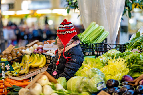 Verkäuferin an einem Obststand mit Jacke, Schal und Mütze schützend vor der Kälte