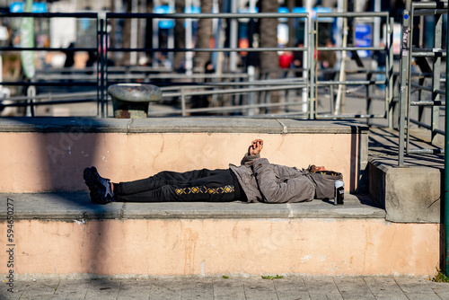 Mann schläft auf Steinbank in der Sonne