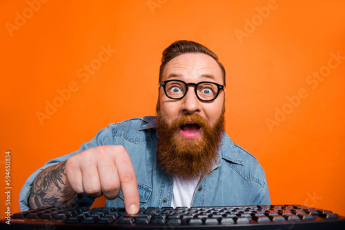 Closeup photo of excited funny businessman try launch his first ecommerce product wear glasses click keyboard isolated on orange color background photo