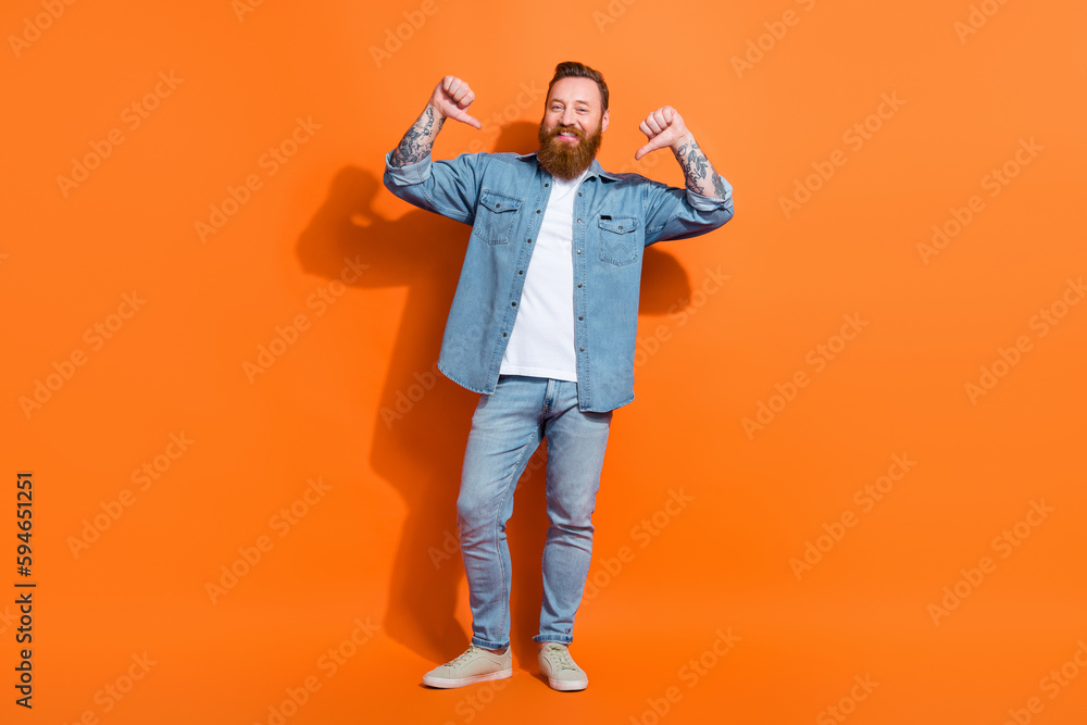 Full length photo of cheerful cool guy dressed denim jacket pointing thumbs himself isolated orange color background Full length photo of cheerful cool guy dressed denim jacket pointing thumbs himself isolated orange color background