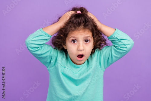 Photo of excited amazed small kid wear turquoise shirt arms head open mouth isolated purple color background