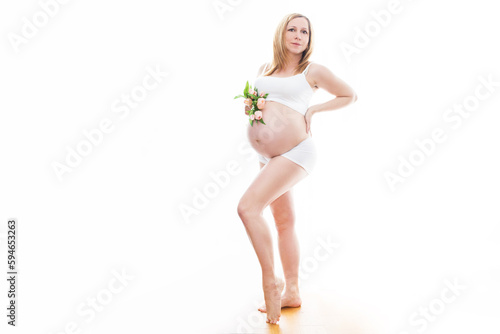 Piękna kobieta w ciąży z kwiatami tulipanów trzyma ręce na brzuchu. Młoda kobieta w sukience czeka na narodziny dziecka. Ciąża, macierzyństwo, dzień matki