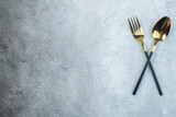 Elegant cutlery set on the left side on gray background with distressed surface with free space