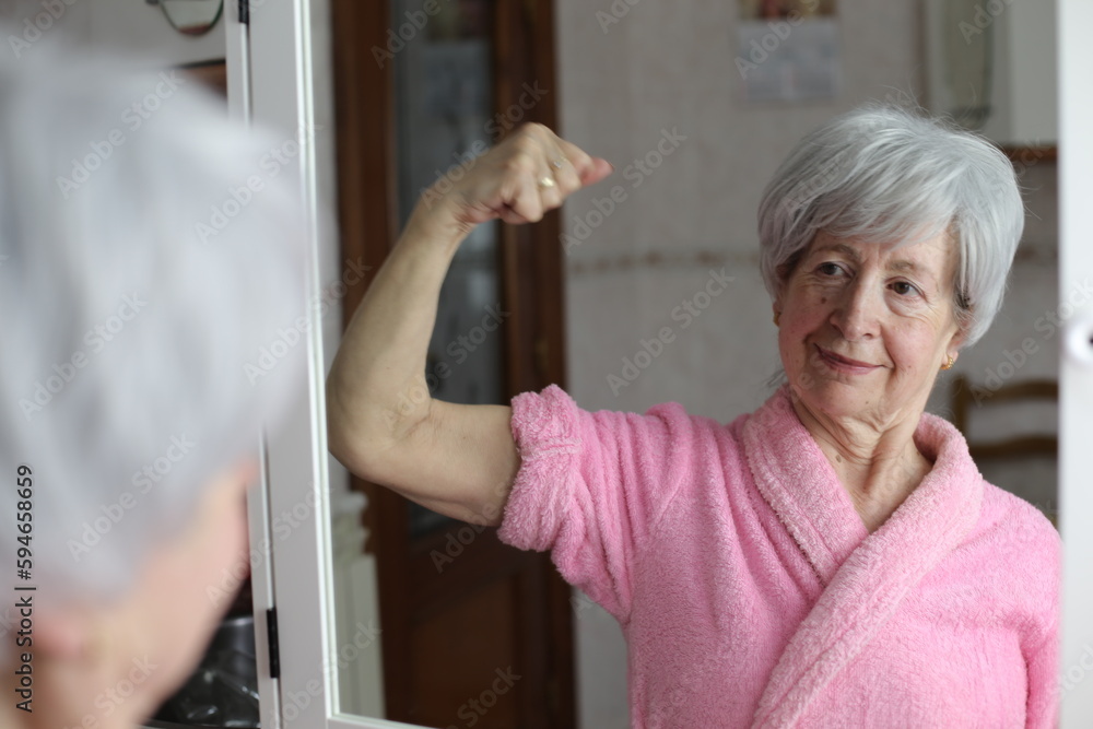 Senior woman flexing biceps in the mirror Senior woman flexing biceps in the mirror