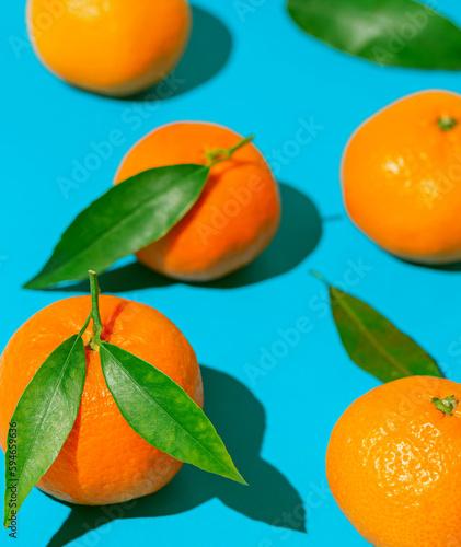 Creative compisition made of fresh orange tangerins on bright blue background. Healthy food concept. Summer refreshment theme.