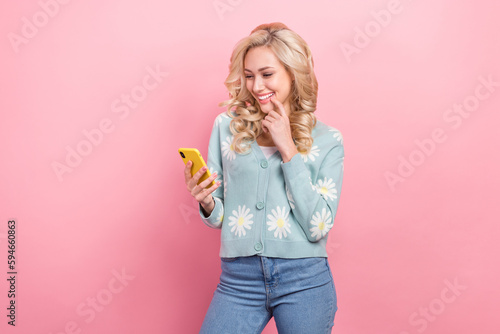 Photo of funny curls youngster glamour lady wear blue daisy flowers print cardigan browsing new phone isolated on pink color background