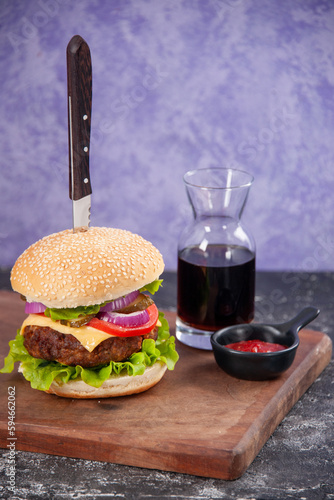 Knife in tasty meat sandwich sauce ketchup on wooden cutting board on isolated ice background photo