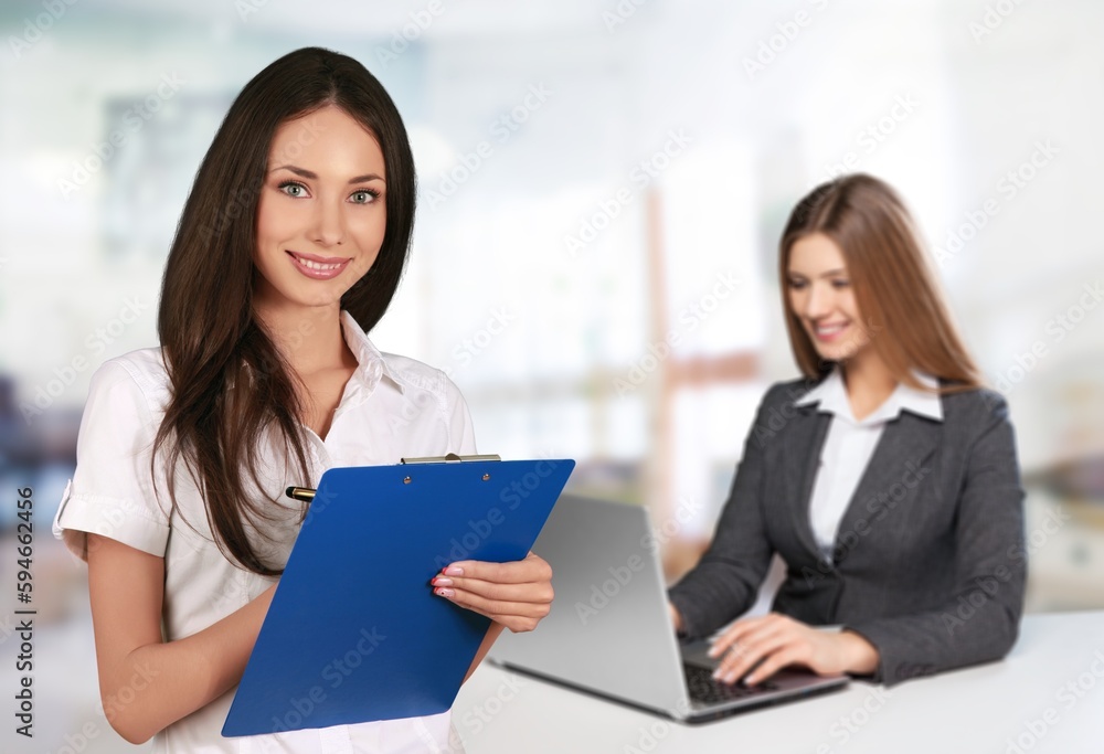 Young business woman with clipboard in office at work Young business woman with clipboard in office at work