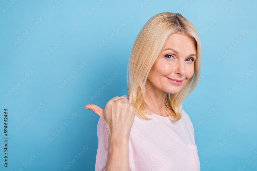 Portrait of pretty lovely lady indicate thumb finger empty space offer isolated on blue color background Portrait of pretty lovely lady indicate thumb finger empty space offer isolated on blue color background