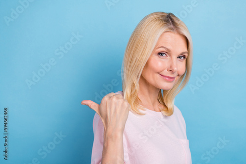 Portrait of pretty lovely lady indicate thumb finger empty space offer isolated on blue color background