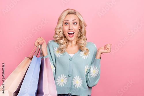 Portrait of impressed delighted person hold store mall bags raise fist isolated on pink color background