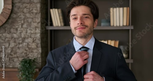 Portrait of handsome businessman getting ready by adjusting necktie in the office photo