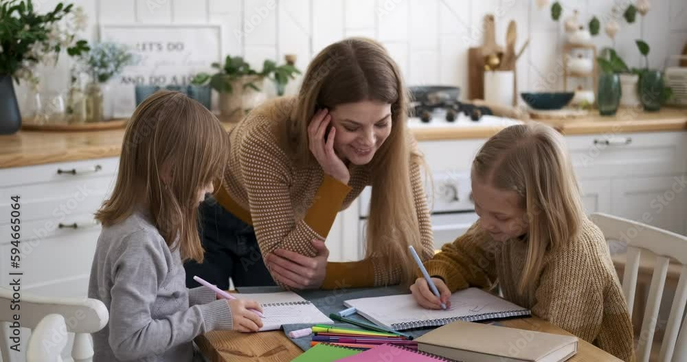 Video „Smiling young mother standing at table and helping children in ...