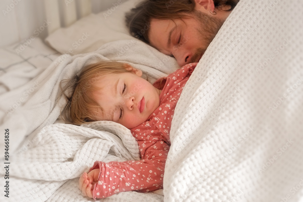 Father and his little daughter toddler girl sleeping together. Healthy sleep. Happy Loving family parent and child sleeping white bed at home. Authentic lifestyle fatherhood moments. Single dad life Father and his little daughter toddler girl sleeping together. Healthy sleep. Happy Loving family parent and child sleeping white bed at home. Authentic lifestyle fatherhood moments. Single dad life