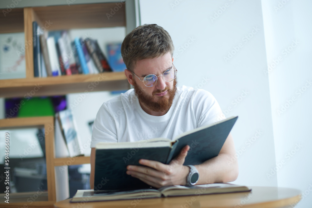 Portrait of serious concentrated guy, young man in glasses college or university student is study hard in library, prepare to exam, lesson Portrait of serious concentrated guy, young man in glasses college or university student is study hard in library, prepare to exam, lesson