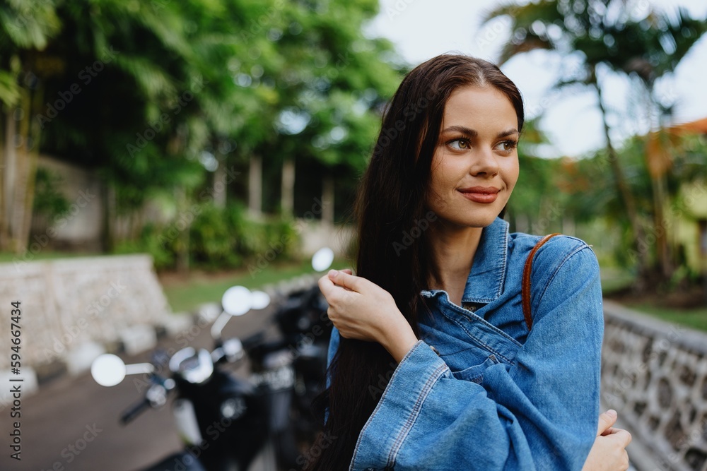 Portrait of a woman brunette smile with teeth walking outside against a backdrop of palm trees in the tropics, summer vacations and outdoor recreation, the carefree lifestyle of a freelance student. Portrait of a woman brunette smile with teeth walking outside against a backdrop of palm trees in the tropics, summer vacations and outdoor recreation, the carefree lifestyle of a freelance student.