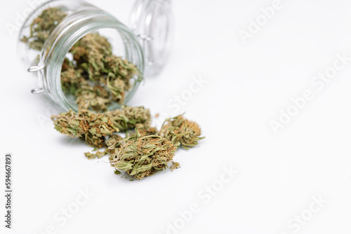 Dry cannabis buds flower outside of a jar on a white background. Concept of marijuana plantation for medical and business