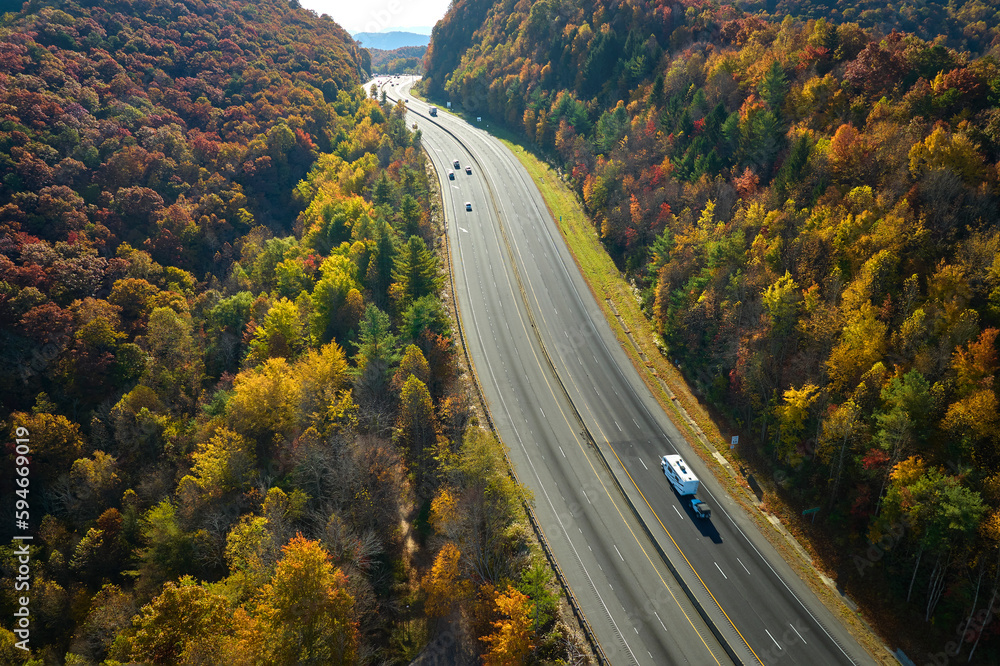 Obraz premium Aerial view of I-40 freeway in North Carolina leading to Asheville through Appalachian mountains in golden fall with fast moving trucks and cars. Interstate transportation concept