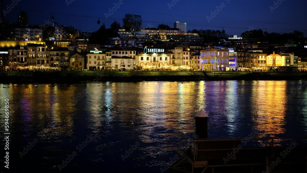 A beautiful dusky lights falls on the city. a riverbank neighborhood is beautifully lit while some distant people are walking by the promenade. a 4K video clip, April 4th, 2023. Porto, Portugal. A beautiful dusky lights falls on the city. a riverbank neighborhood is beautifully lit while some distant people are walking by the promenade. a 4K video clip, April 4th, 2023. Porto, Portugal.