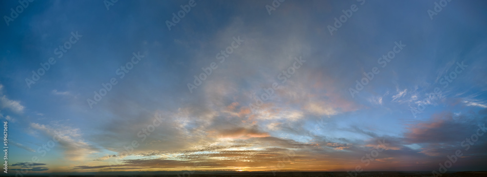 Obraz premium Bright colorful sunset sky with vivid smooth clouds illuminated with setting sun light spreading to horizon