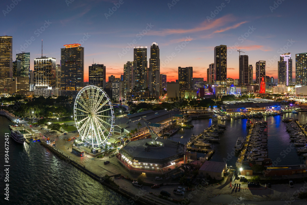 Miami marina harbor and skyscrapers of Brickell, city financial center. Skyviews Miami Observation Wheel at Bayside Marketplace with reflections in Biscayne Bay water and US urban landscape at night - obrazy, fototapety, plakaty 