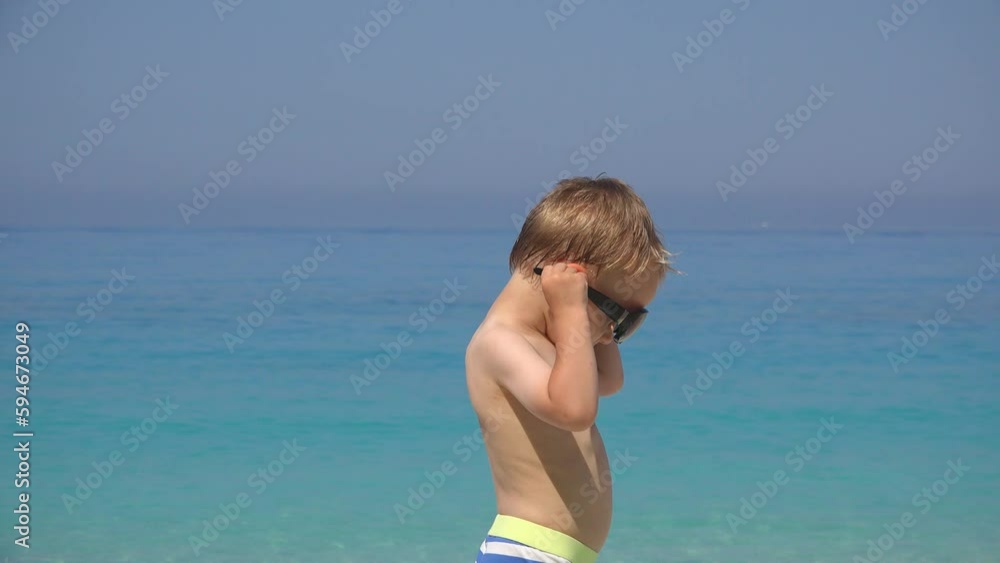 Little boy on beach trying to put on the sunglasses Little boy on beach trying to put on the sunglasses