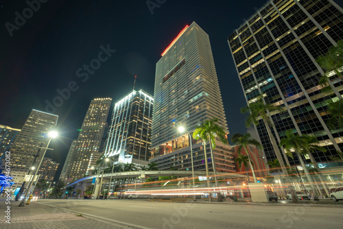 Night urban landscape of downtown district of Miami Brickell in Florida USA. Illuminated high skyscraper buildings and street with car trails and Metrorail traffic in modern american megapolis