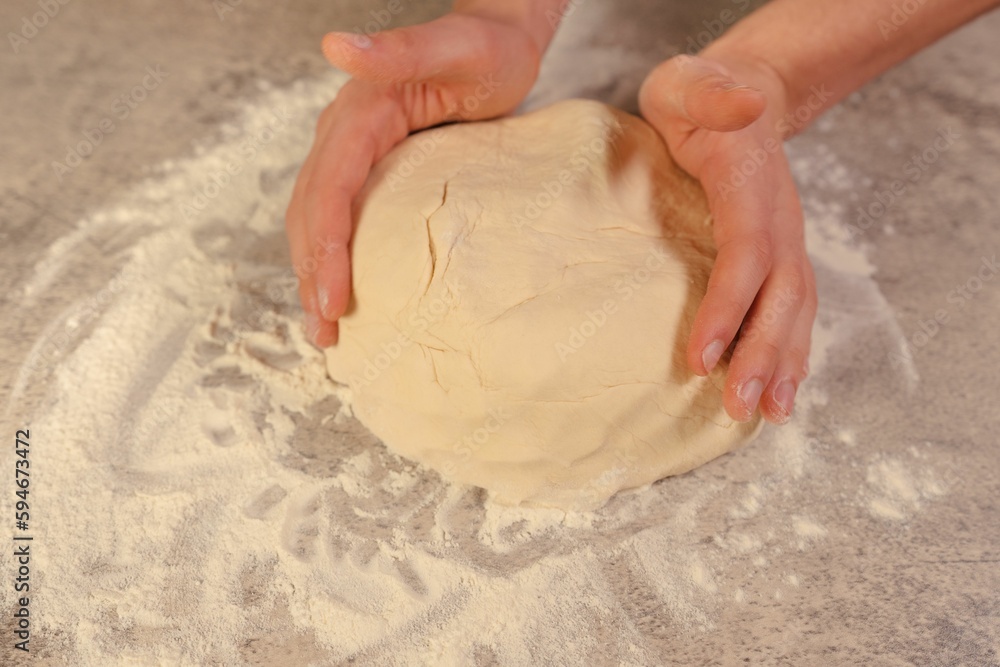 Person kneading a ball of dough, preparing to bake a delicious treat Person kneading a ball of dough, preparing to bake a delicious treat