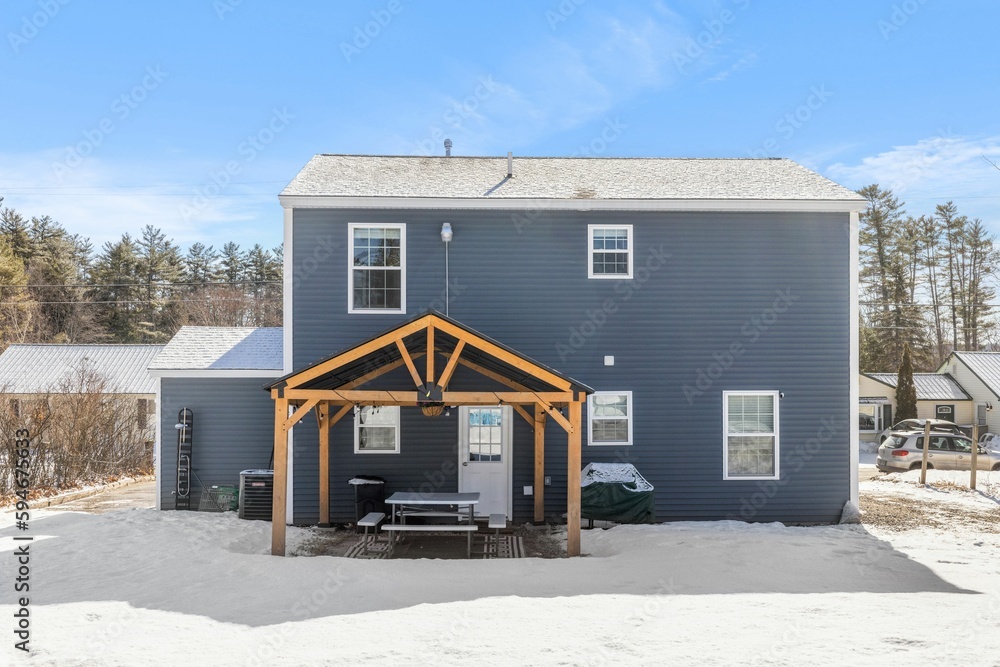 Contemporary gray two-story residential house with a wood-covered patio in the foreground Contemporary gray two-story residential house with a wood-covered patio in the foreground