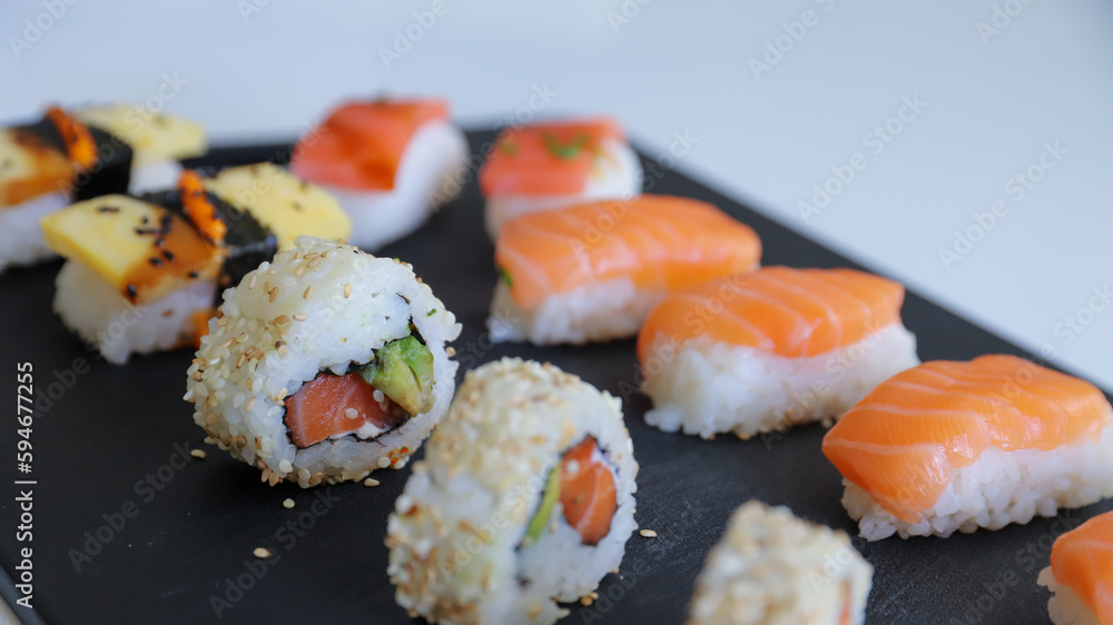 close up of sushi set on dark tray close up of sushi set on dark tray