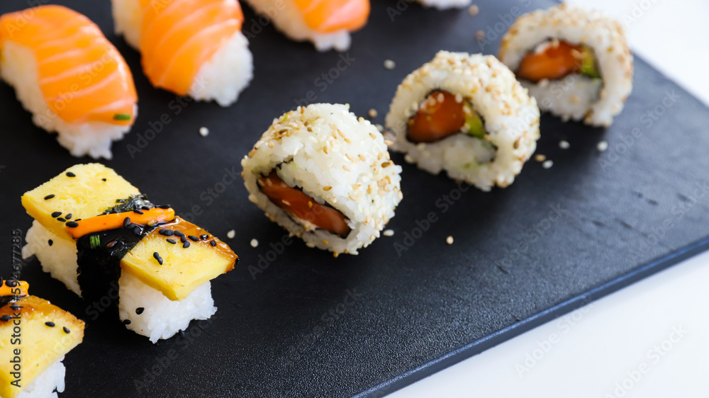 close up of sushi set on dark tray close up of sushi set on dark tray