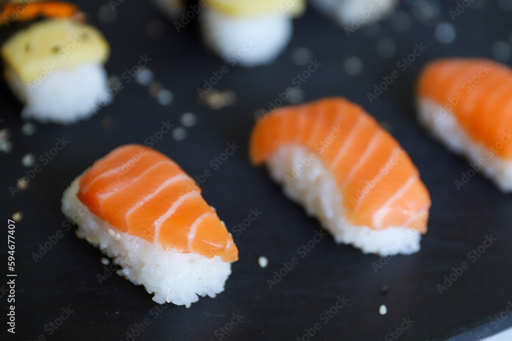 close up of sushi set on dark tray close up of sushi set on dark tray
