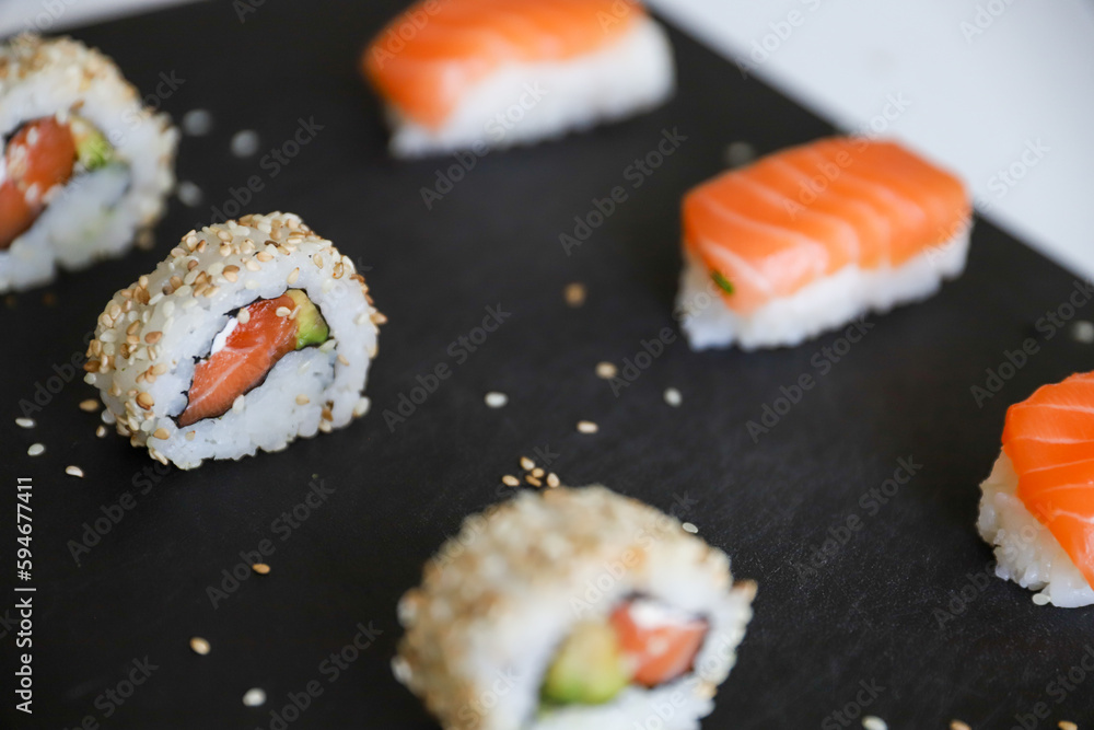 close up of sushi set on dark tray close up of sushi set on dark tray