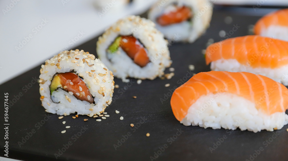 close up of sushi set on dark tray close up of sushi set on dark tray