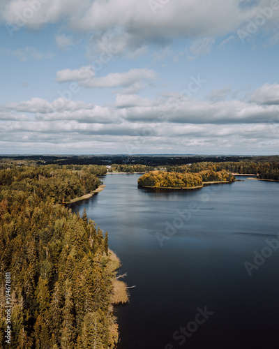 Aerial Drone Photo Of Lake And Early Autumn Colorful Forest Trees With Blue Sky With Clouds