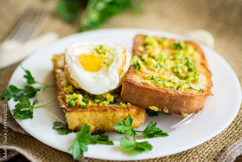 Fried croutons in batter with garlic and herbs and a fried egg in a plate.