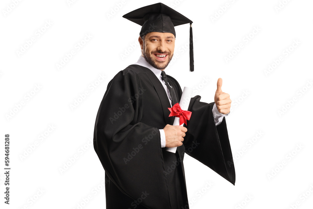 Happy male student wearing a graduation gown, holding a diploma and gesturing thumbs up Happy male student wearing a graduation gown, holding a diploma and gesturing thumbs up