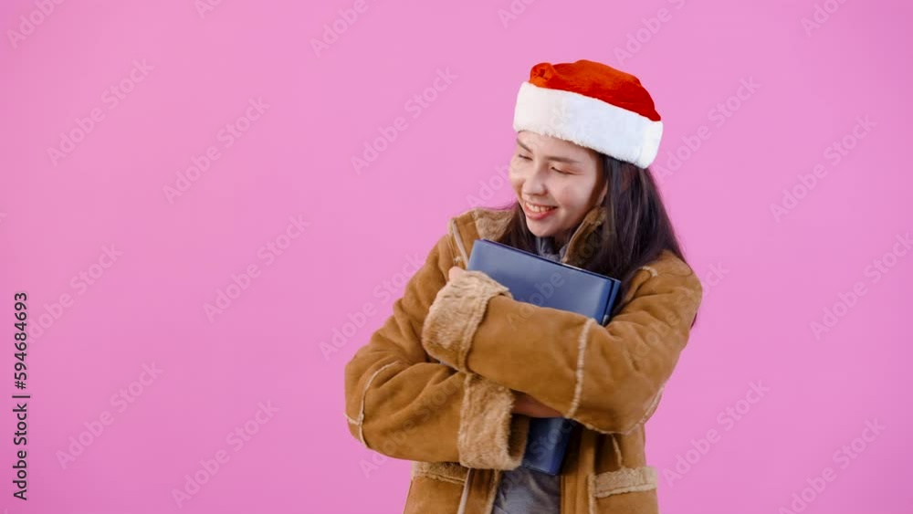 4K, woman in long-sleeved shirt with fluffy because cold on christmas night, hugged received gift box smiles, looks happily on night christmas, Isolated indoor studio on pink background. 4K, woman in long-sleeved shirt with fluffy because cold on christmas night, hugged received gift box smiles, looks happily on night christmas, Isolated indoor studio on pink background.